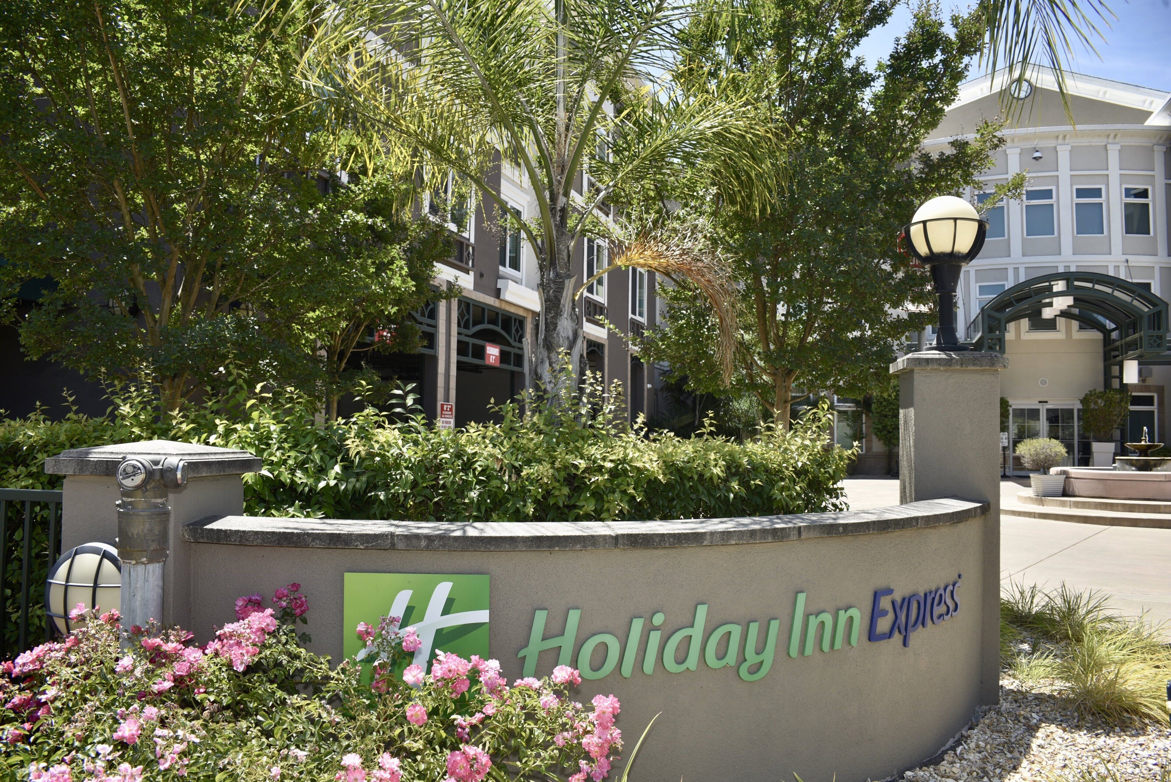 A Holiday Inn Express sign with a landscaped area in front, including a fountain and flowering plants.