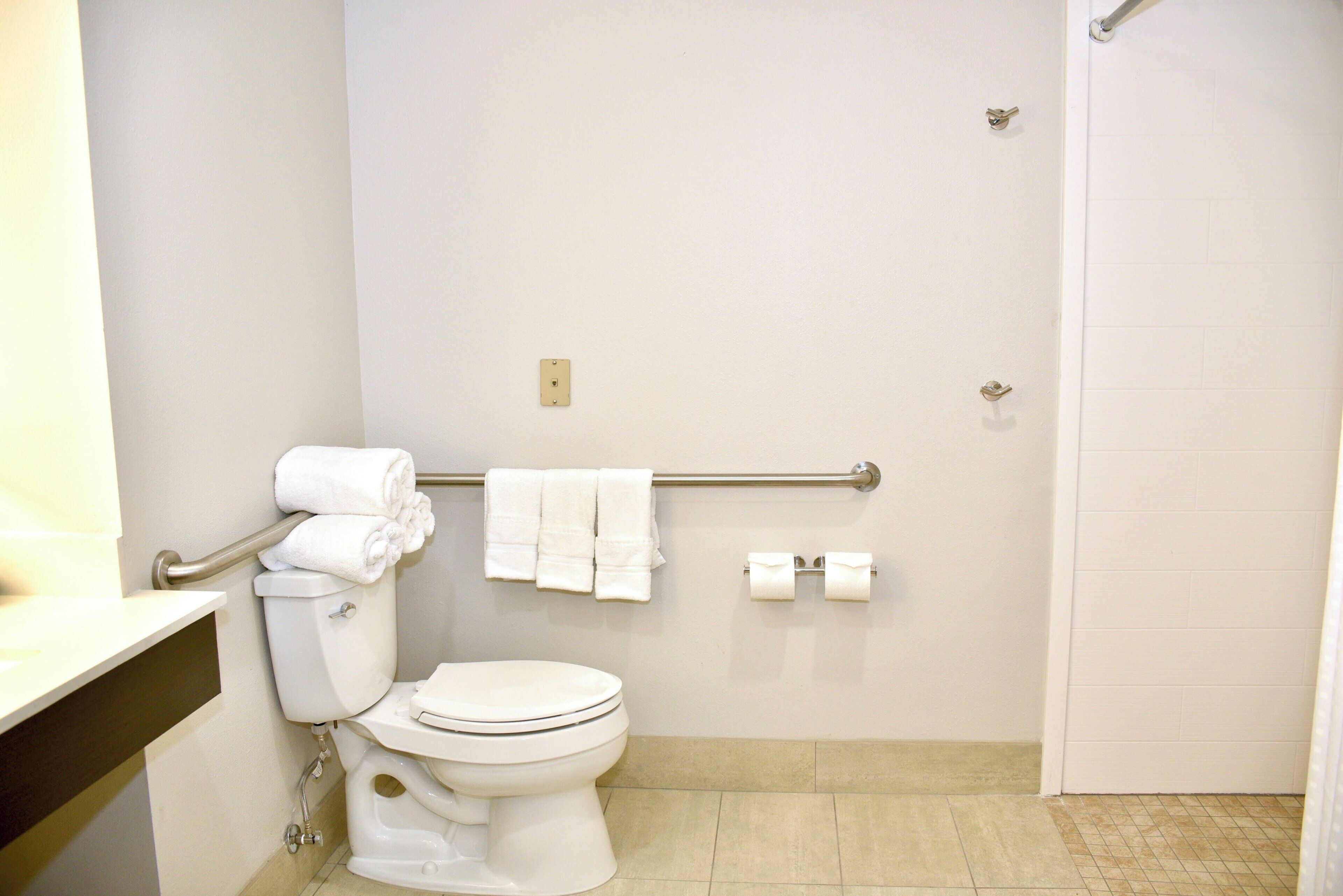 A standard hotel bathroom with a toilet, a towel rack, and a toilet paper holder.