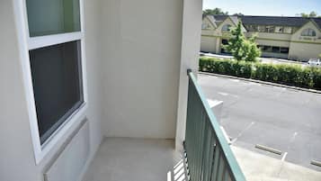 A balcony with a view of a parking lot and a building with a sign that reads 'Café'.