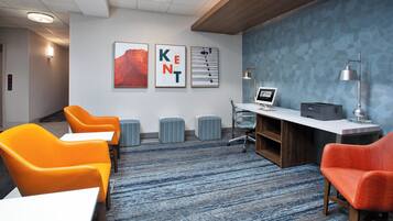 Un espace de bureau moderne comprenant un comptoir d’accueil, deux chaises orange, un ordinateur et un mur à motifs bleus.