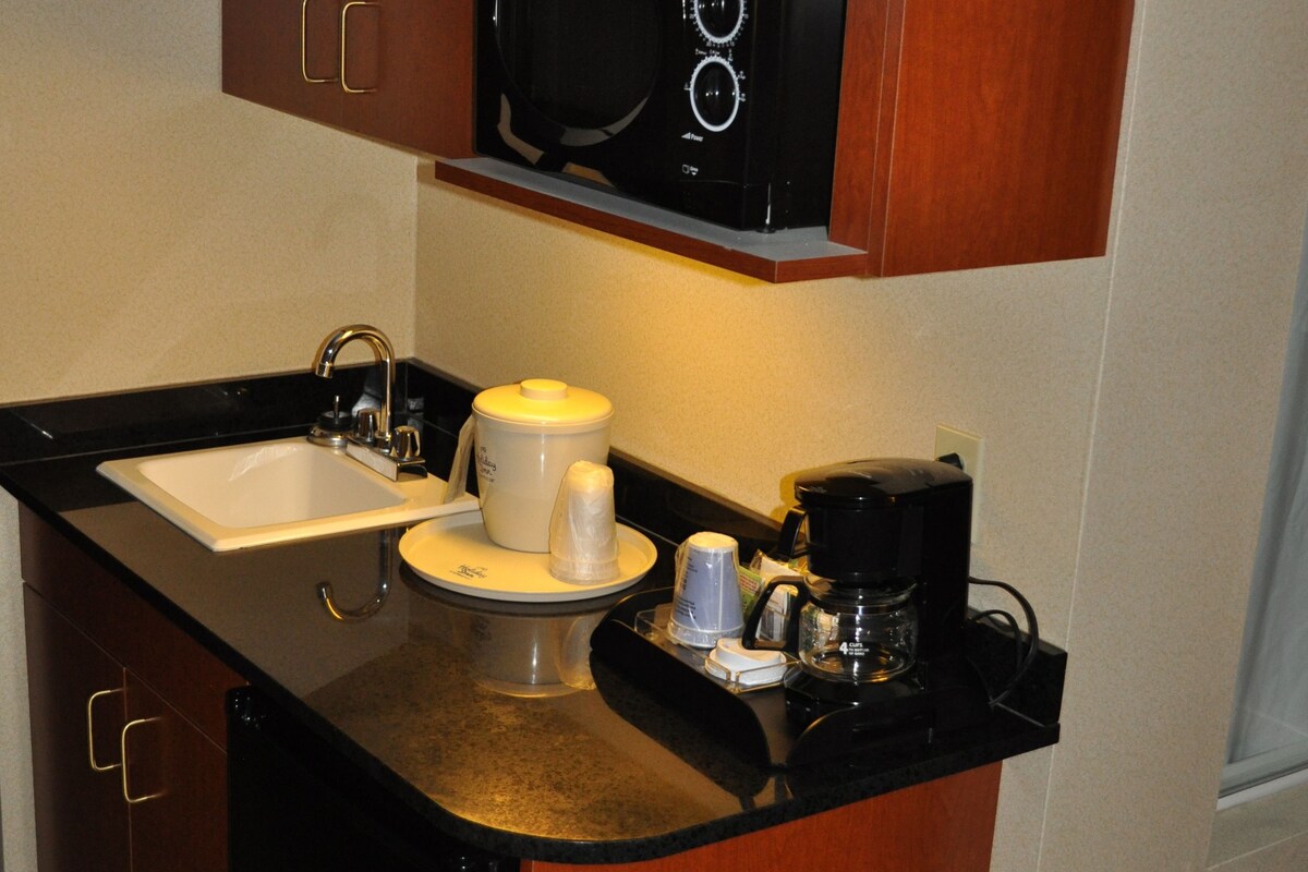 A compact kitchen with a microwave, coffee maker, and a sink.