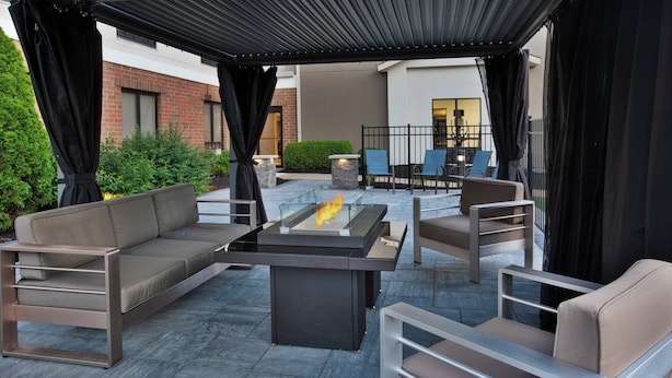 An outdoor patio area with a fire table, seating, and a view of the building in the background. - Holiday Inn Express & Suites Kent - University Area by IHG (Kent)