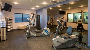 A gym with exercise equipment, a water dispenser, and a mirror.