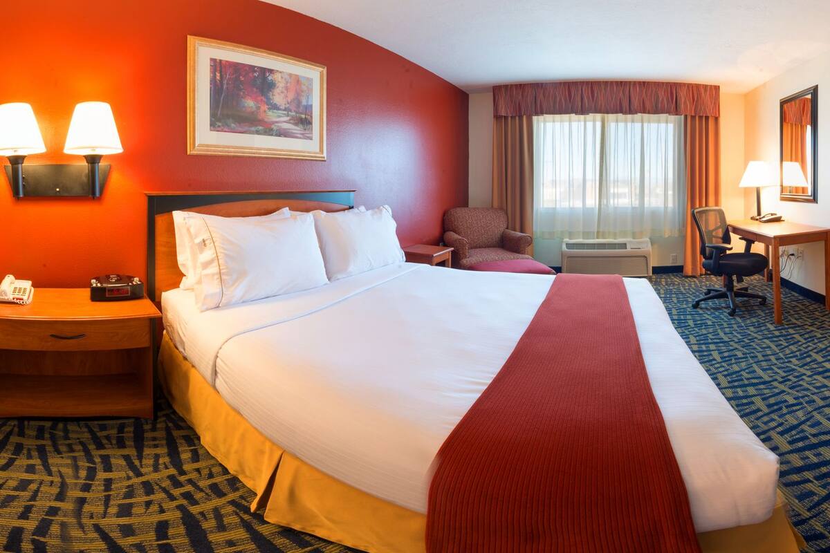A hotel room with two beds, a TV, a desk, and a chair.
