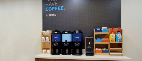 A coffee station with multiple coffee dispensers, a hot water dispenser, and various coffee products on shelves.