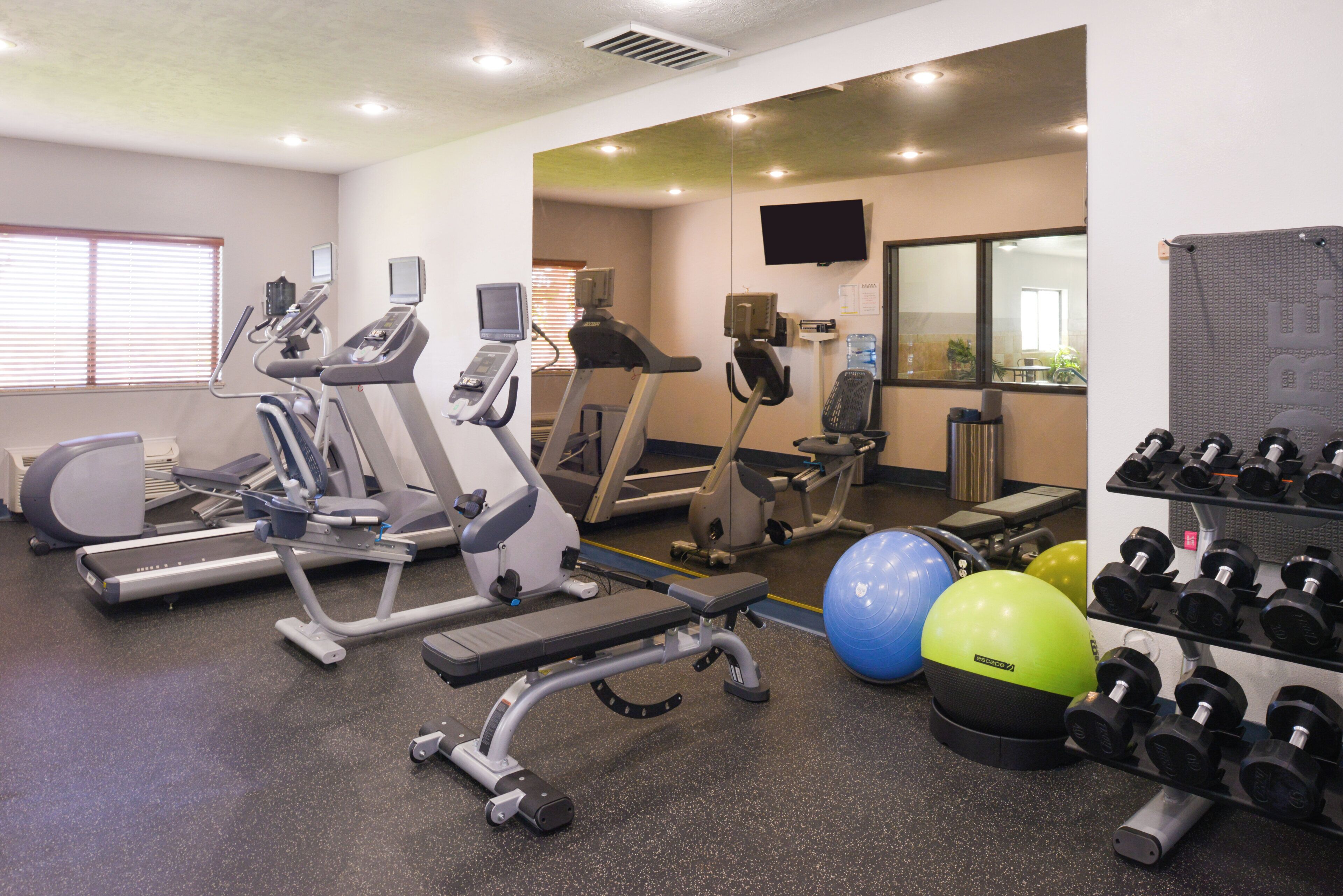 Un gimnasio con cintas de correr, elípticas, una bicicleta estática y pesas libres.