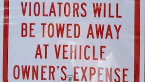 A red and white no trailer parking sign with a warning that violators will be towed at their own expense.