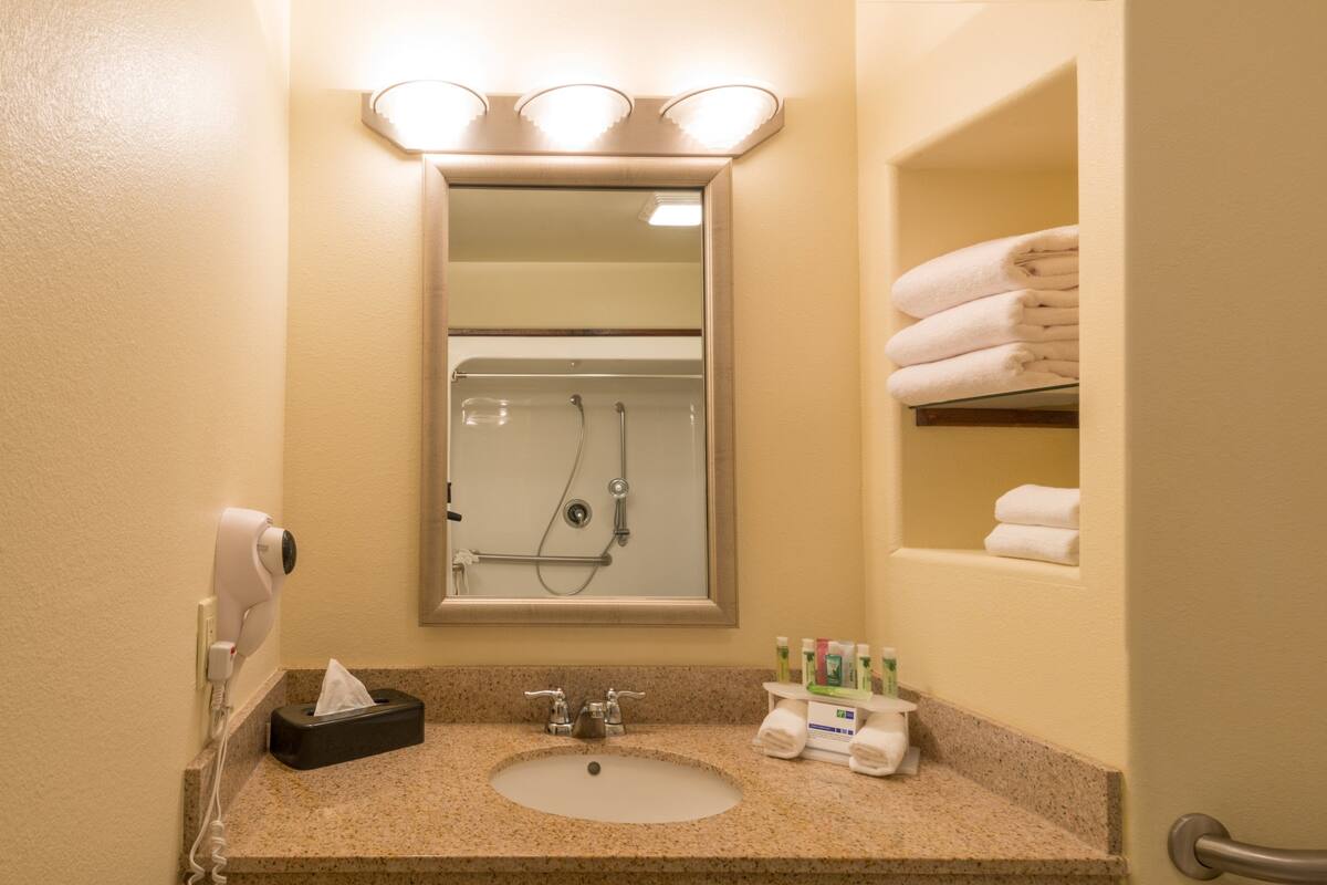 A bathroom with a sink, mirror, and towel rack.