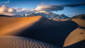 A desert landscape with sand dunes and a mountain in the background.