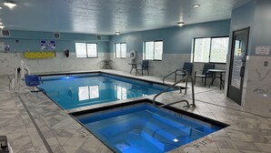 An indoor swimming pool with clear water, tiled walls, and a ceiling with recessed lighting.