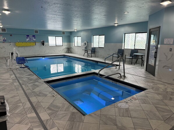 An indoor swimming pool with clear water, tiled walls, and a ceiling with recessed lighting.