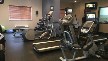 A gym with treadmills, elliptical machines, and free weights.
