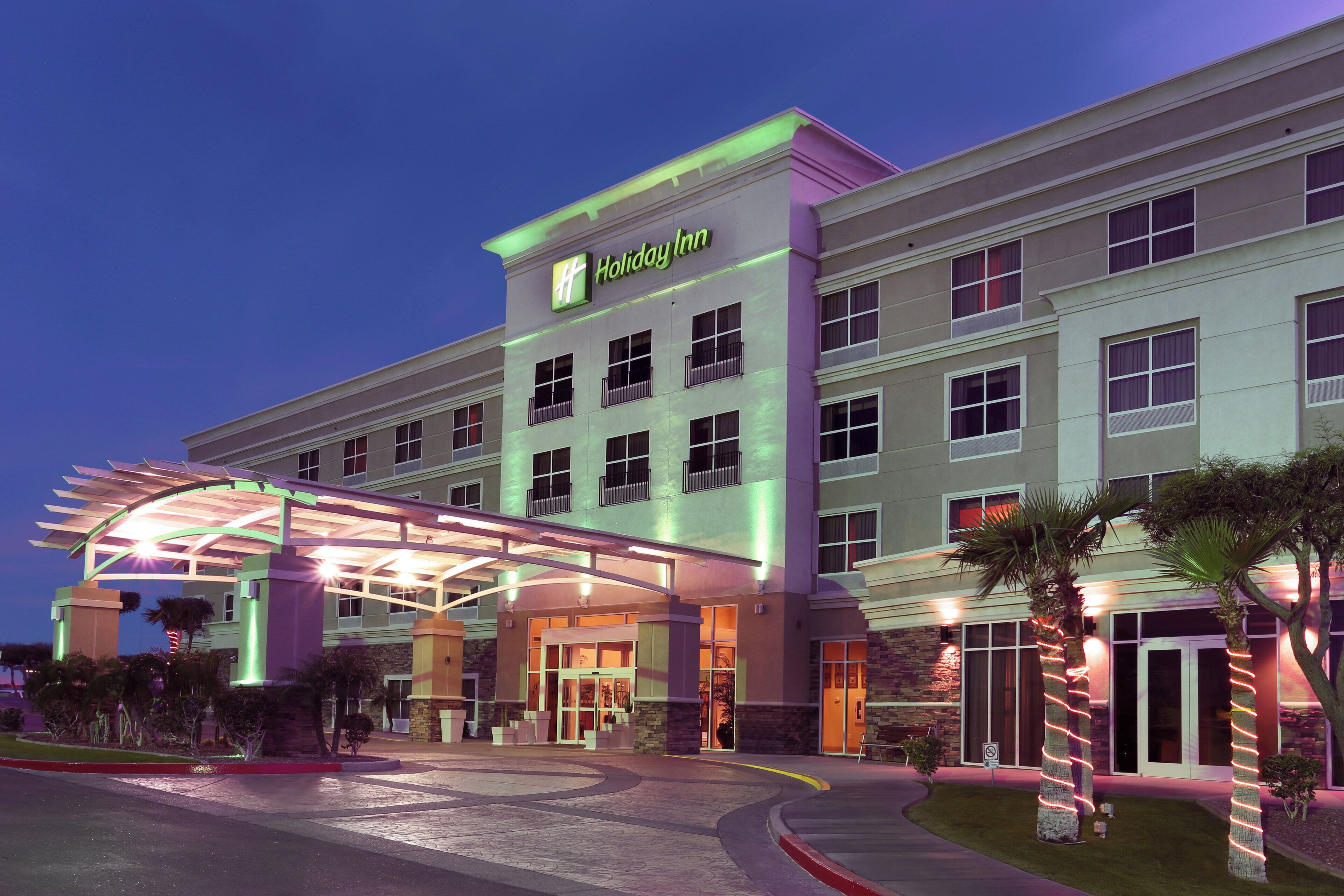 A Holiday Inn hotel with a covered entrance, multiple floors, and a parking area.