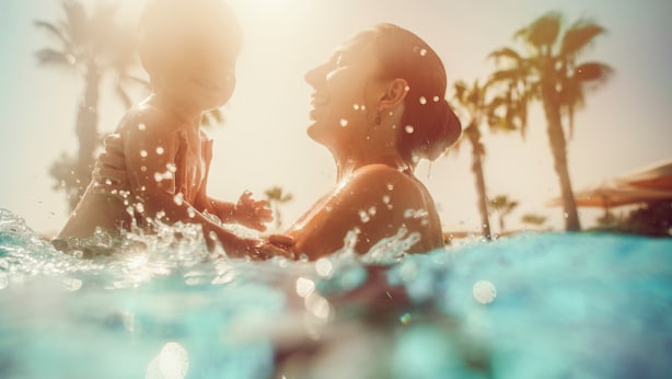 Un couple dans une piscine, avec des palmiers en arrière-plan.
