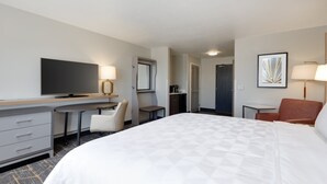 Une chambre d’hôtel comprenant un lit, un bureau, une chaise, une télévision et une salle de bain.
