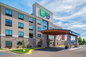 Un hôtel Holiday Inn Express & Suites doté d’une façade en pierre, de nombreuses fenêtres et d’une entrée abritée.