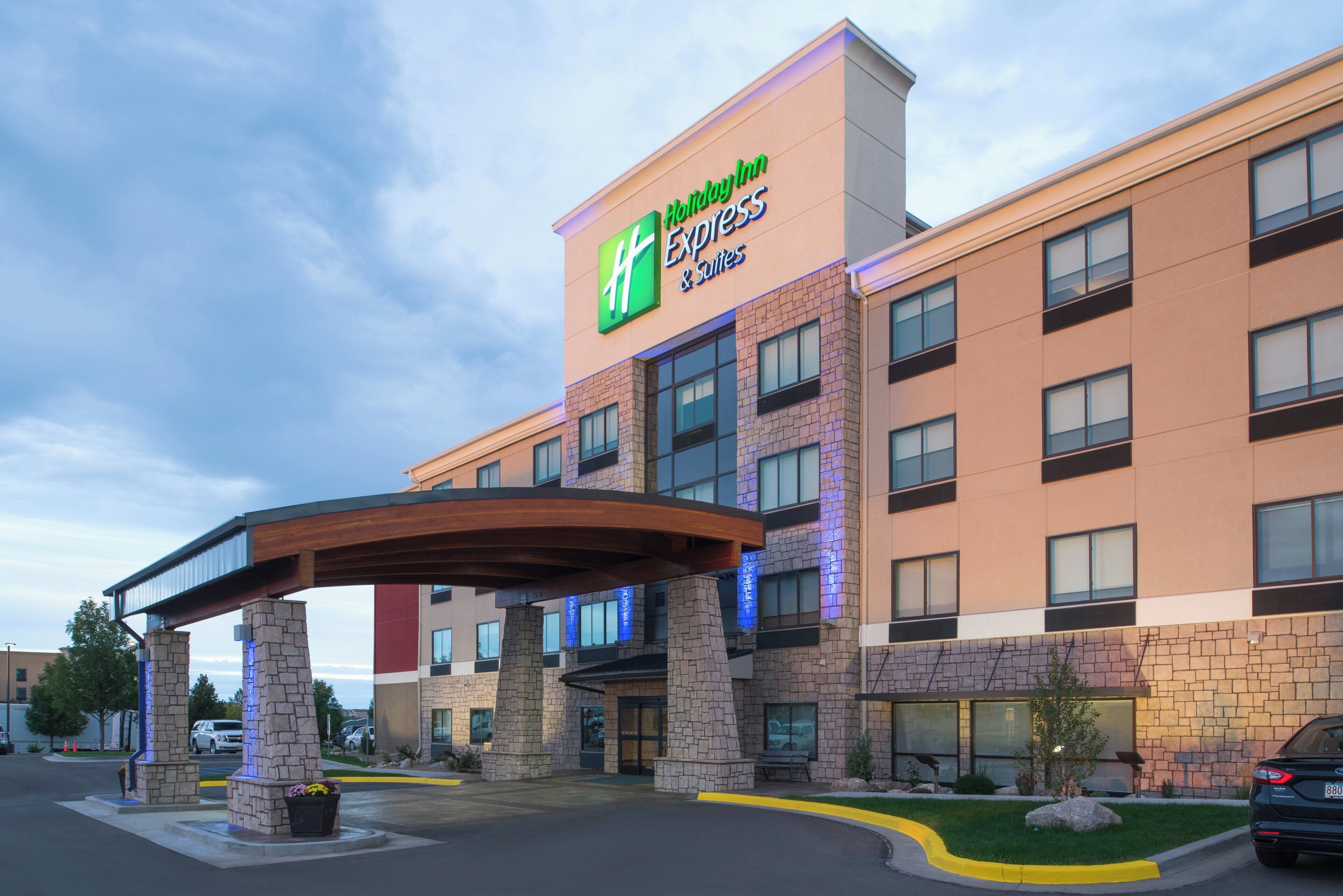 Ein Holiday Inn Express Gebäude mit einer Steinfassade, mehreren Fenstern und einem überdachten Eingangsbereich.
