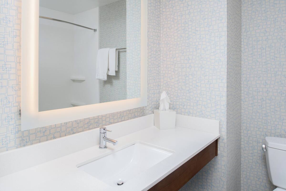 A bathroom with a white sink, a mirror, and a toilet.