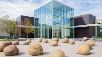 Un bâtiment moderne doté de grandes fenêtres en verre et d’une cour intérieure agrémentée de gros rochers.