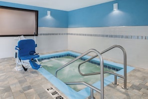 A swimming pool with a blue and white tiled interior, a blue chair, and a metal pool ladder. - Holiday Inn Express Hotel & Suites Bismarck by IHG (Bismarck)