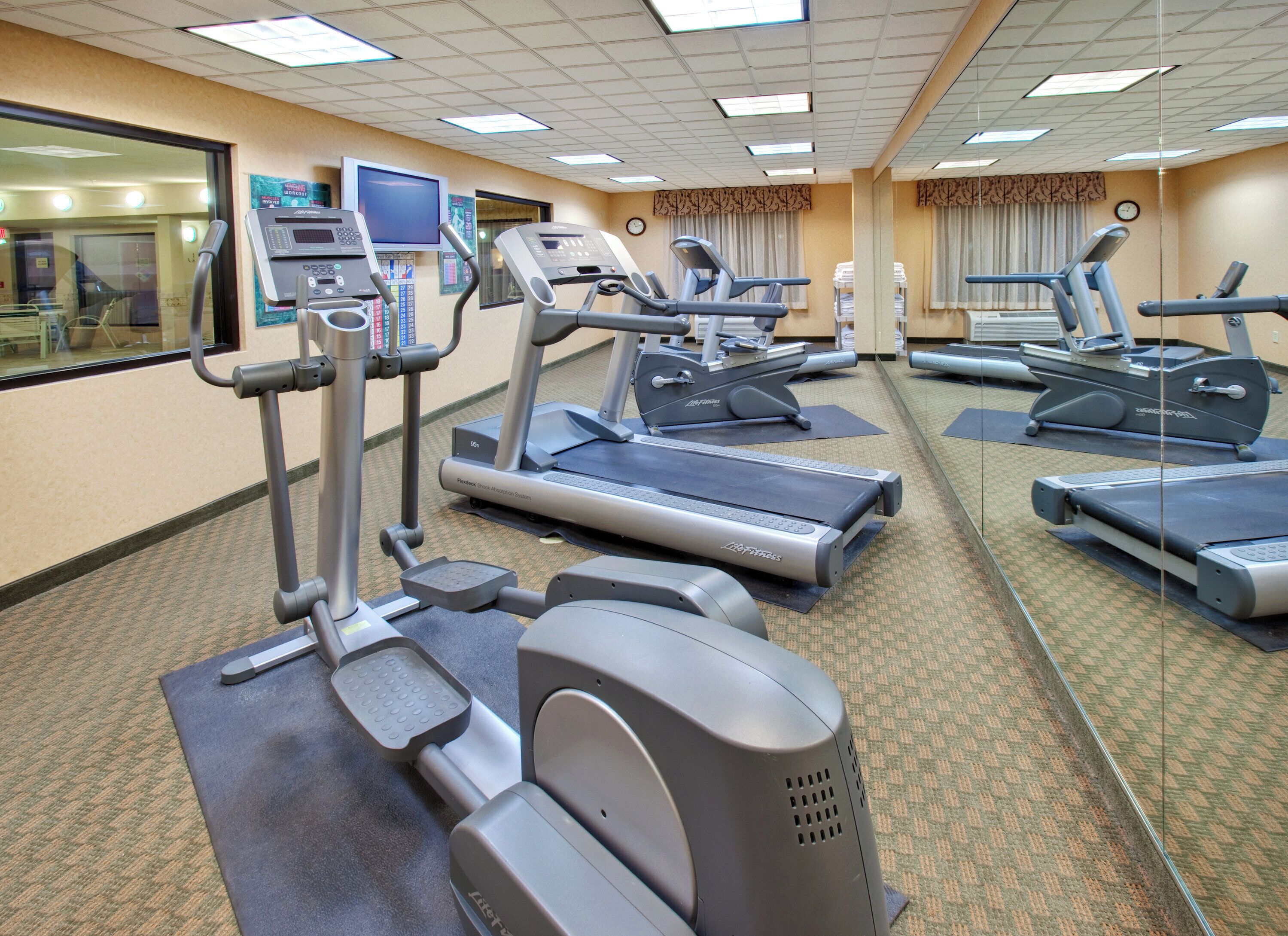 A gym with treadmills, ellipticals, and a weight machine.