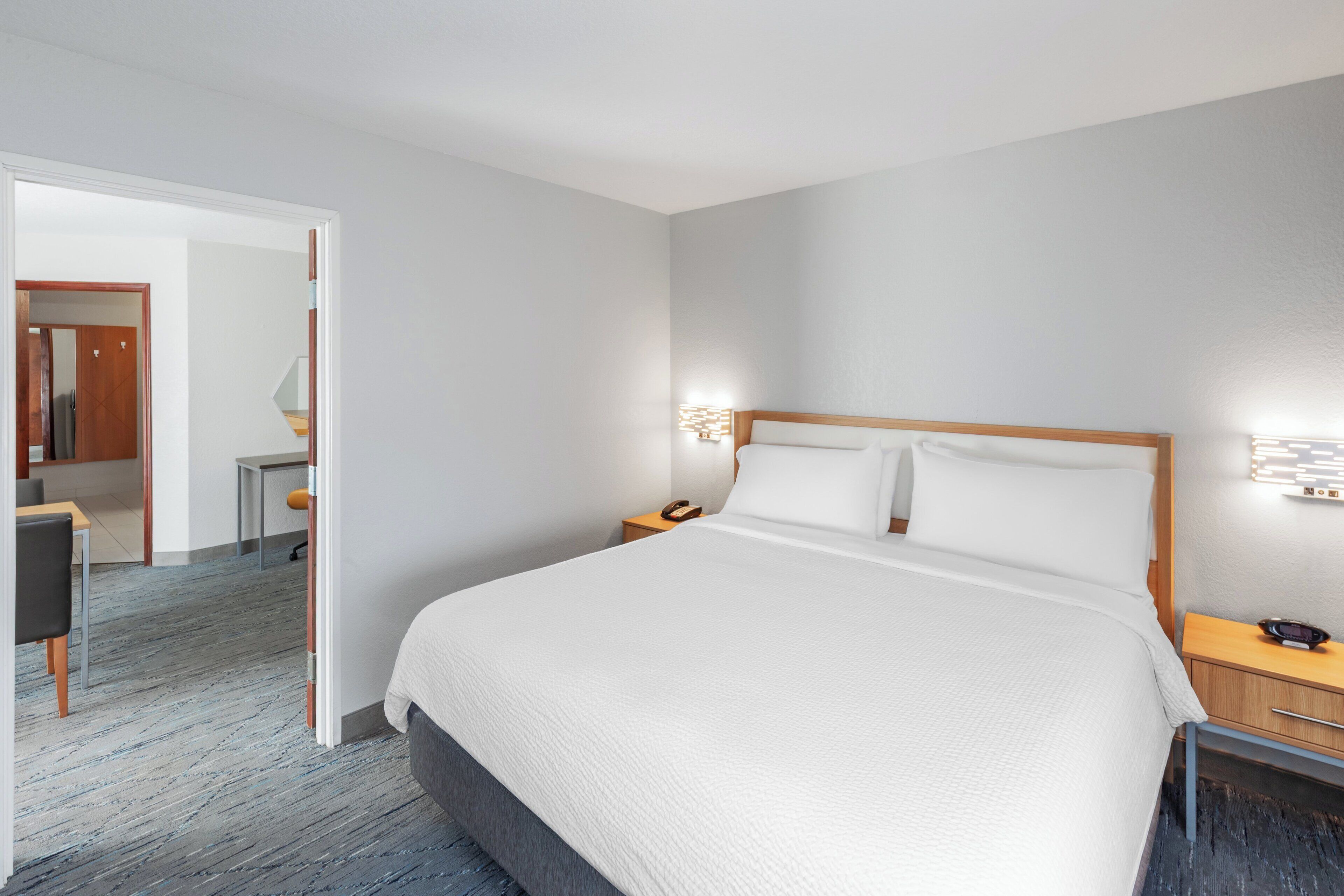A hotel room with a large bed, bedside tables, a desk, and a chair.