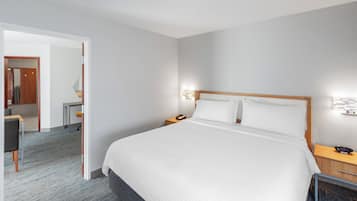 A hotel room with a large bed, bedside tables, a desk, and a chair.