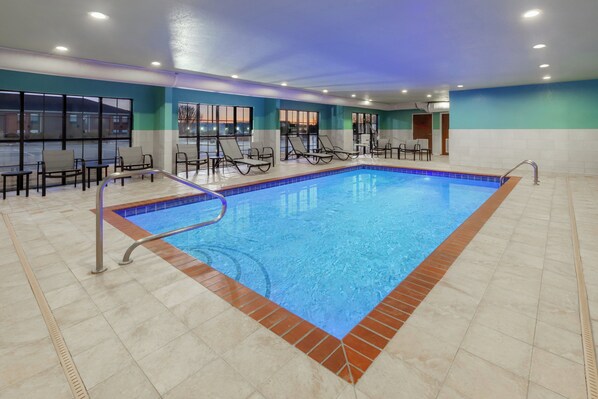 An indoor swimming pool with lounge chairs and tables, surrounded by large windows. - Holiday Inn Express & Suites Lonoke by IHG (Lonoke)