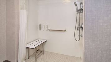 A shower area with a handheld showerhead, a handheld shower attachment, and a grab bar.