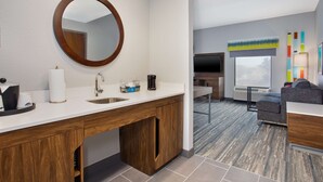 A modern bathroom with a wooden vanity, a round mirror, and a sink. - Hampton Inn & Suites Lady Lake/The Villages (Lady Lake)