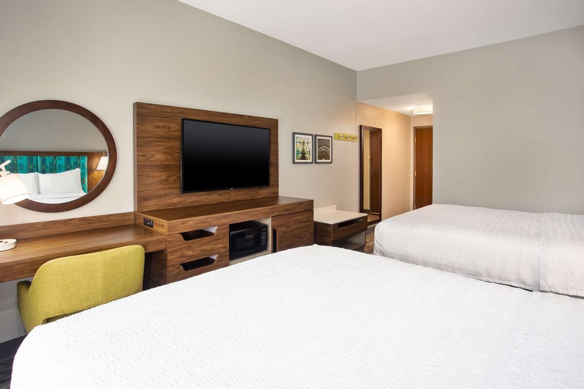 A hotel room with a bed, a desk with a computer, a television, and a microwave.