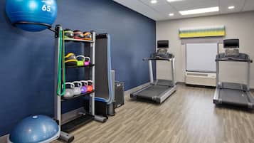Une salle de remise en forme équipée de tapis de course, d’un banc de musculation et d’un grand ballon d’exercice.
