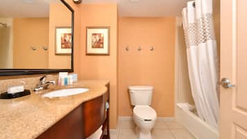 A bathroom with a sink, mirror, toilet, and bathtub.
