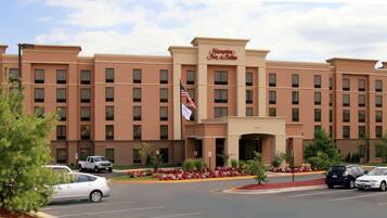 Un hotel Hampton Inn & Suites con una fachada simétrica, múltiples ventanales y una entrada central.