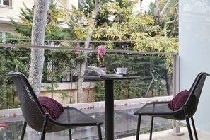 A balcony with two chairs, a table, and a vase with flowers. - The Y Hotel (Kifisia)