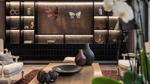 Una sala moderna con un panel de madera oscura, un televisor de pantalla plana grande y varios objetos decorativos, incluyendo jarrones y una escultura de mariposa.