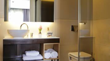 Un baño moderno con lavamanos grande, espejo y cabina de ducha de vidrio.