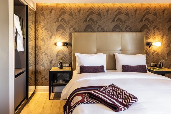 A hotel room with a large bed, two nightstands, a wardrobe, and a patterned wallpaper. - The Y Hotel (Kifisia)