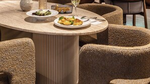 Una mesa redonda con sillas, un florero y platos de comida.