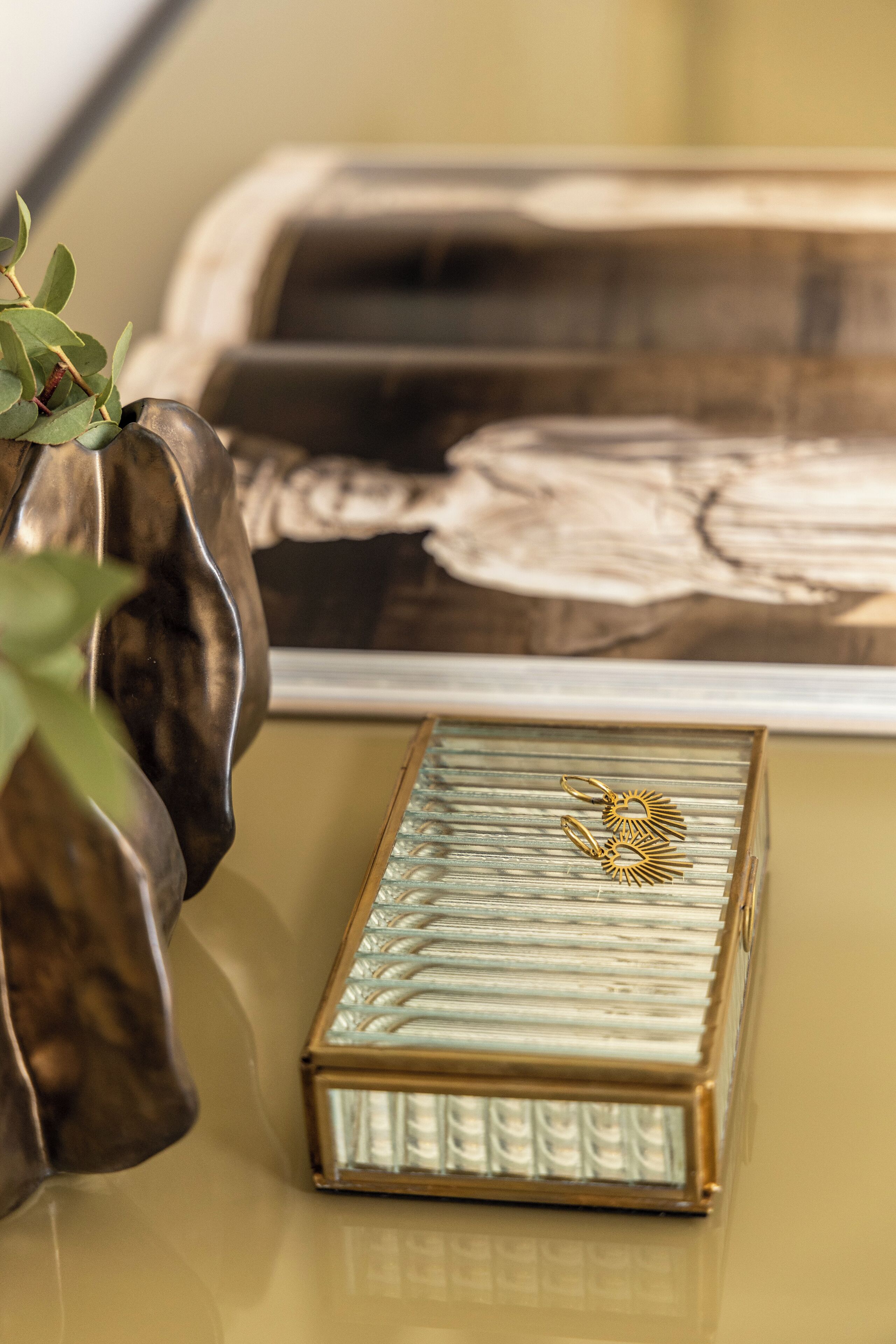 A decorative glass box with a gold design on a reflective surface.