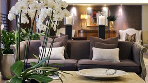 Una sala de estar moderna con un sofá marrón, cojines blancos, una mesa de centro y un jarrón con orquídeas blancas.