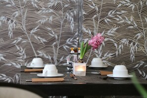 A table set with white cups, a candle, and a pink flower. - The Y Hotel (Kifisia)