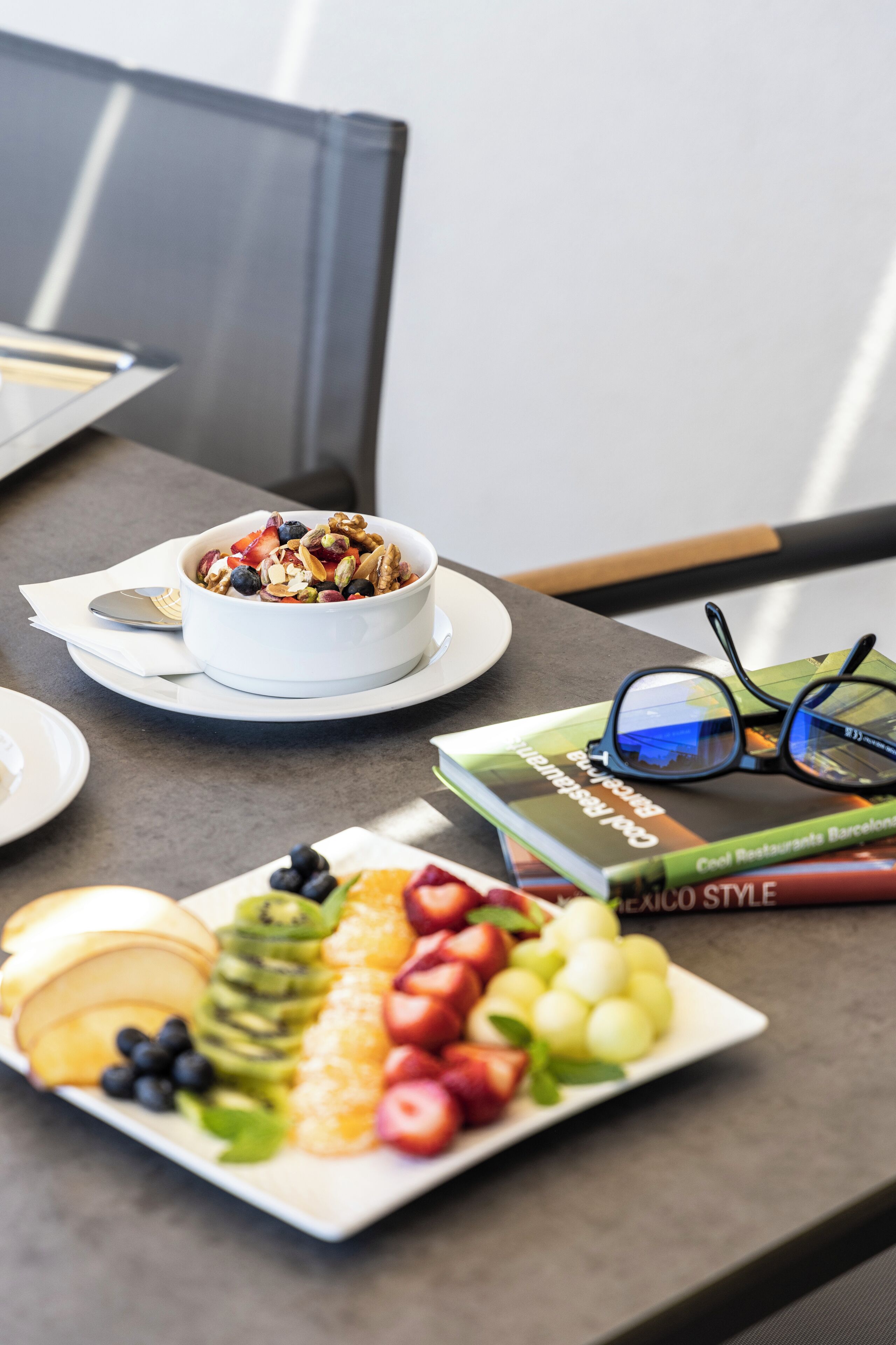 A breakfast setting with a bowl of cereal and a plate of fruit.