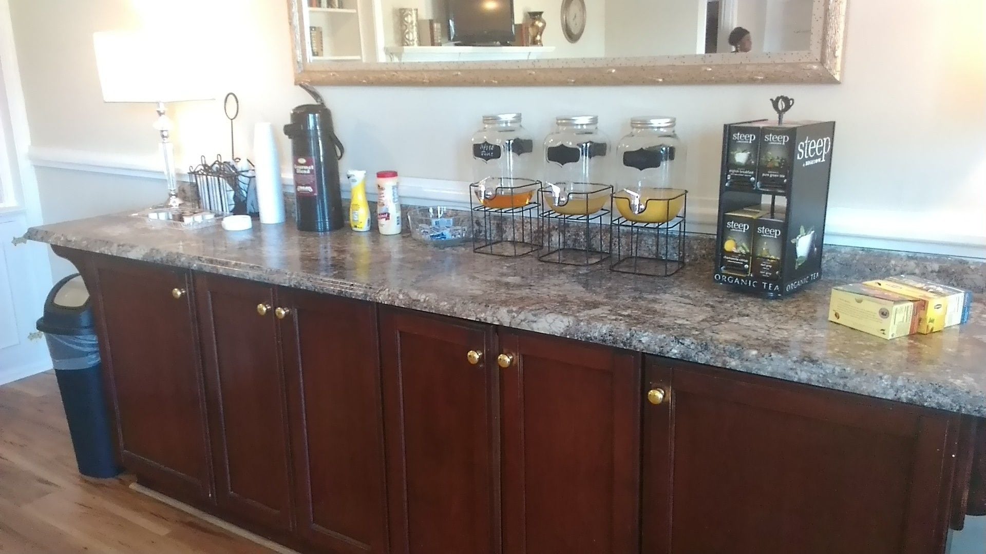 A kitchen counter with a coffee maker, jars, and tea boxes.