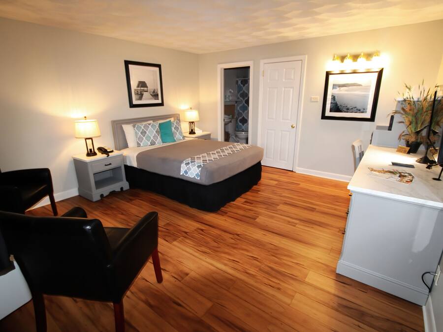 A hotel room with a bed, bedside tables, a desk, a chair, and a television.