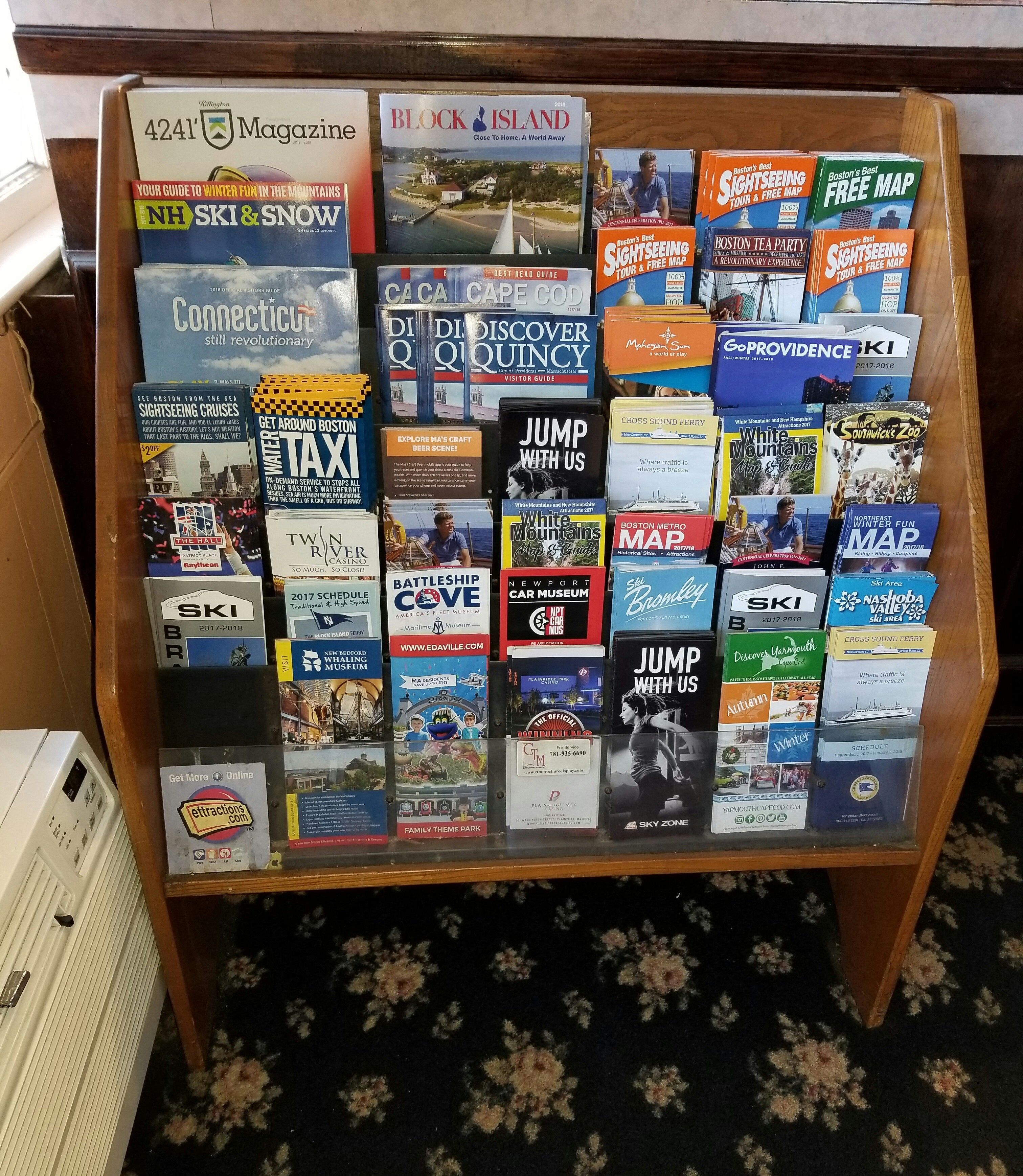 Esposizione di diverse guide turistiche e mappe su un supporto in legno.