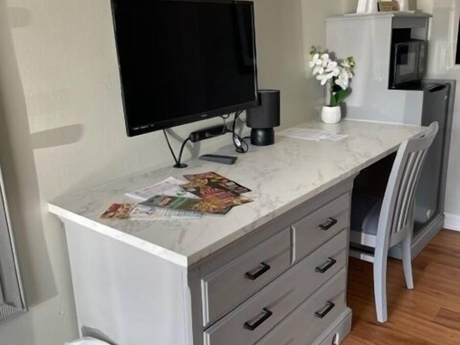 A modern room with a marble countertop, a television, a small cabinet, and a chair.