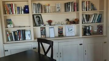 A room with a large bookshelf filled with books and decorative items, a dining table with chairs, and a patterned carpet.