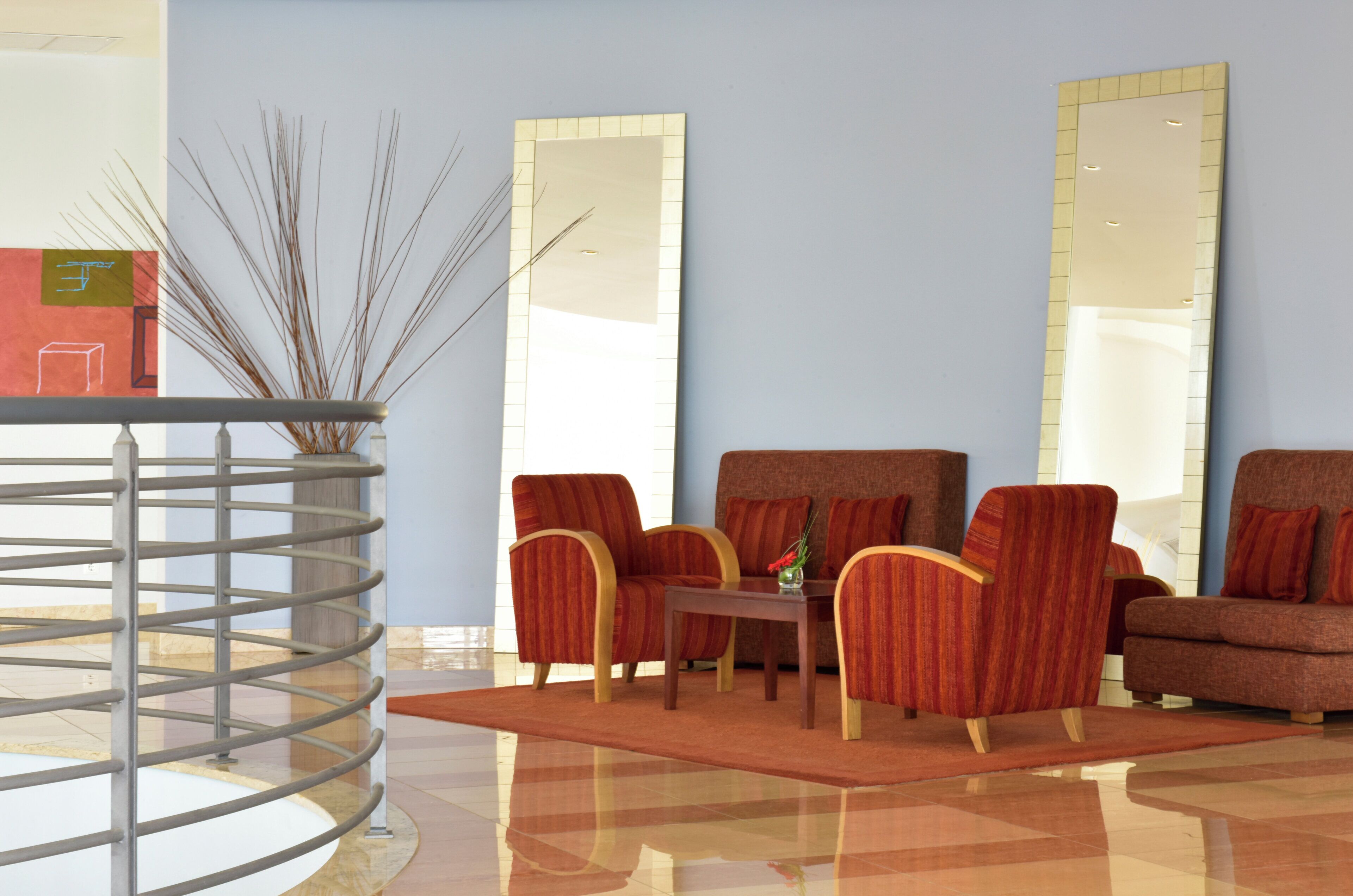 Een moderne woonkamer met een bank, fauteuils, een salontafel en een decoratieve vaas.