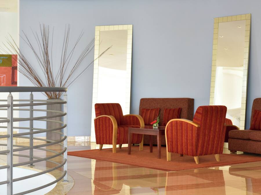 Een moderne woonkamer met een bank, fauteuils, een salontafel en een decoratieve vaas.
